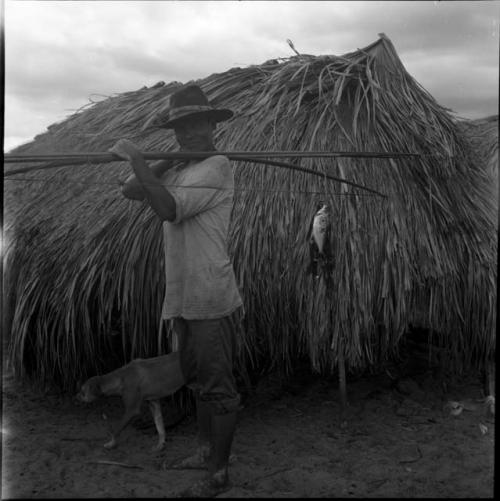 Village, housing, house living: Yaruro house, man carrying fishing pole with fish on the line