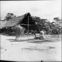 Village, housing, house living: people outside wooden structure with thatched roof