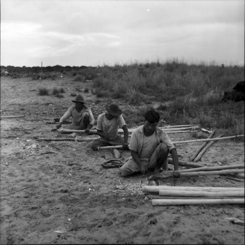 Houses and house buildings: three men constructing a building, notching poles