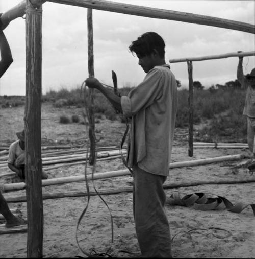 Houses and house buildings: constructing a building, man cutting rope