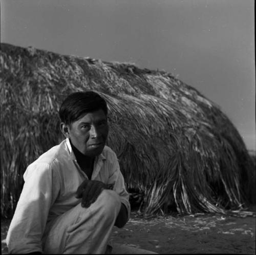 Portraits of people: man in front of thatched building