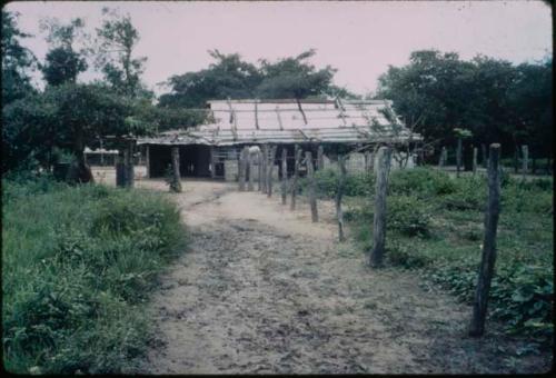 Dirt path to white building, possibly a barn