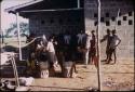 People grouped outside cinder block building