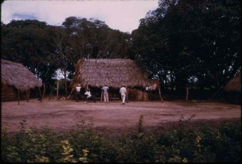 Men outside thatched building