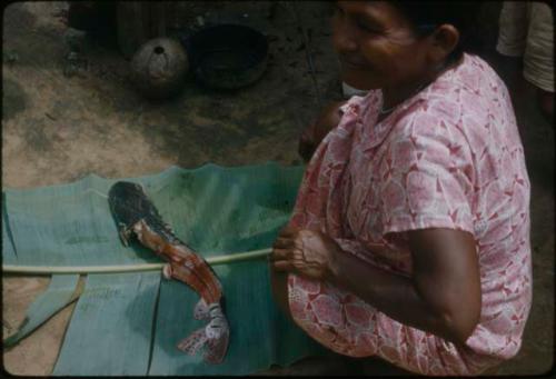 Woman in a pink dress flaying fish