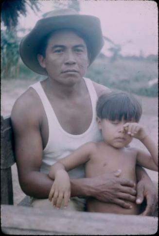 Man wearing hat holding child