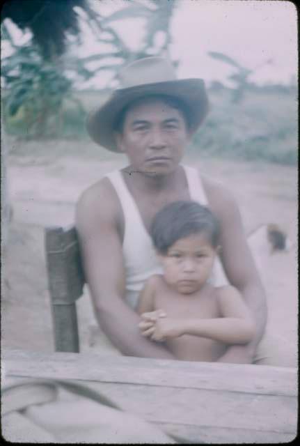 Man wearing hat holding child