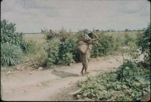 Woman carrying sacks along dirt path