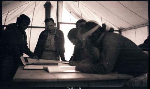 Hopi men looking at papers and books with Watson Smith in the pottery tent