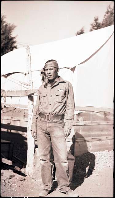 Leland Dennis standing in front of a tent, wearing a headband