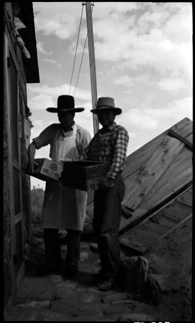 Lin Thompson in western hat with Luke in front of vegetable cellar.