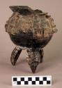 Ceramic tripod jar, moulded human figures, raised incised squares, bird head