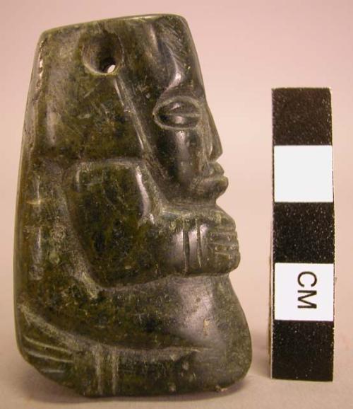 Ground stone pendant, carved kneeling human, perforated at top, greenstone