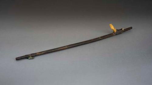 Wooden atlatl with one bone peg in shape of human face and one metal +