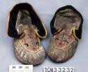 Pair of moccasins of caribou hide (?) with black cloth cuffs trimmed with yellow