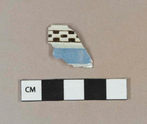 Black on white checkerboard and blue machine turned annularware pearlware vessel body fragment, white paste