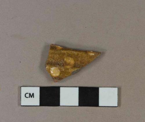 Brown and yellow slip decorated earthenware vessel body fragment, grayish red paste