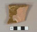 Earthenware, lead glazed, slip decoration, rim sherd; yellow and brown, scratched letters on unglazed exterior possibly "H..."