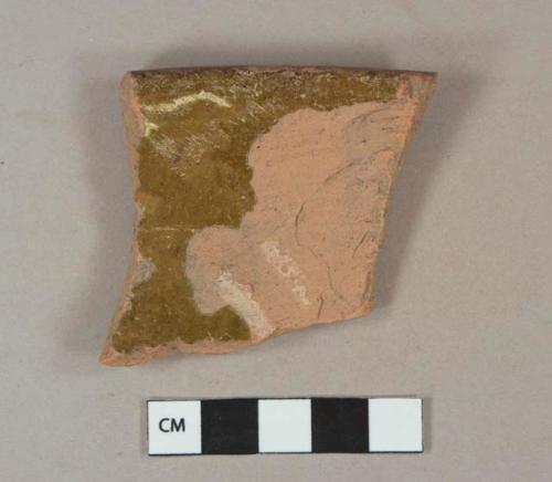 Earthenware, lead glazed, slip decoration, rim sherd; yellow and brown, scratched letters on unglazed exterior possibly "H..."