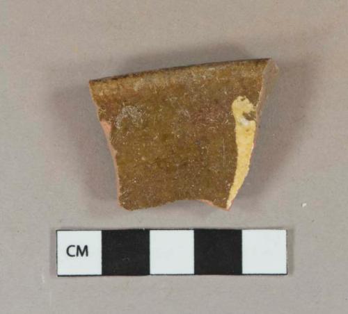 Yellow on brown slip decorated redware vessel rim fragment