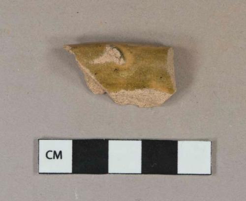 Greenish tan lead glazed earthenware vessel rim fragment, buff paste