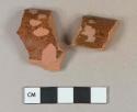 Dark reddish brown lead glazed interior redware vessel rim fragments, unglazed exterior, 1 fragment burned, both fragments mend