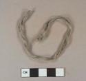 Gray/white cotton tine fragment, knotted in loop