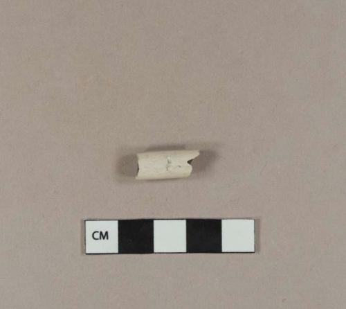 Smoked, undecorated kaolin pipe stem fragment, with tooth mark in it; 7/64" bore diameter