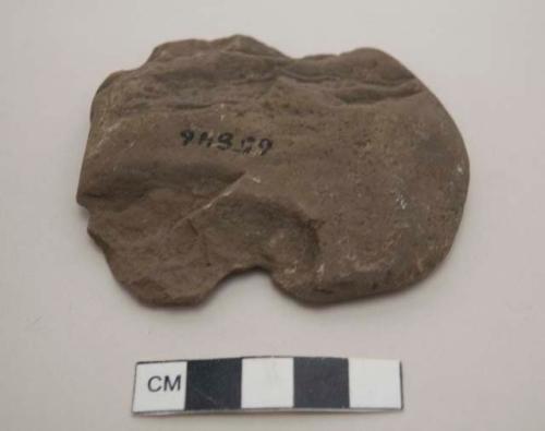 Modified lithic, flat and somewhat round with two opposing notches on the edges