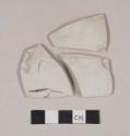Undecorated porcelain body sherds, glazed interior and textured, unglazed exterior; one sherd has possible handle attachment; three sherds crossmend