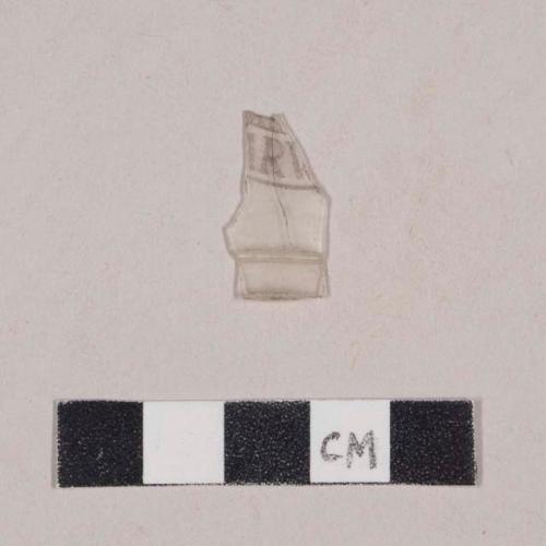 Curved colorless plastic fragment with printed design, including "R", possibly Harvard seal