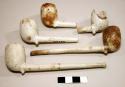 Collection of clay pipe bowls with stems attached.