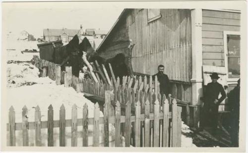 Arctic Voyage of Schooner Polar Bear - Men standing outside building with picket fence
