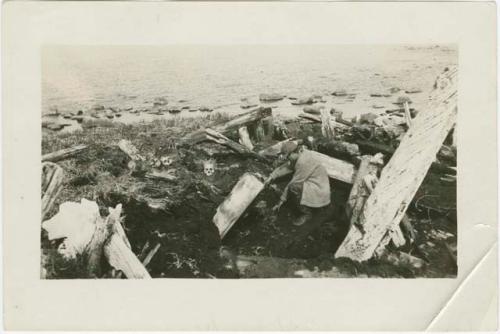 Arctic Voyage of Schooner Polar Bear - Sprague Brooks digging in ruined house, St. Lawrence Island