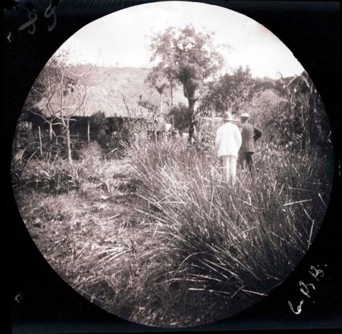 Two men in a grassy area in front of a building