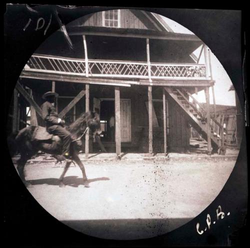 Person riding horse in front of building