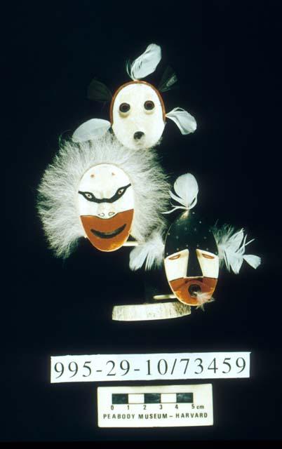 Three miniature carved ivory masks mounted on pole