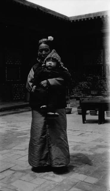 Woman with elaborate headwear, holding baby