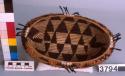 Small oval coiled basket, brown woven design, feather and shell ornament.