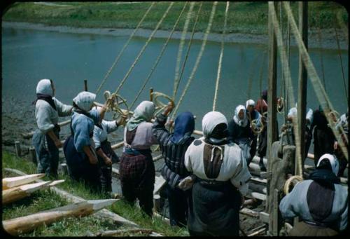 Women using ropes to raise a pole