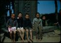 Children sitting in front of stone monument