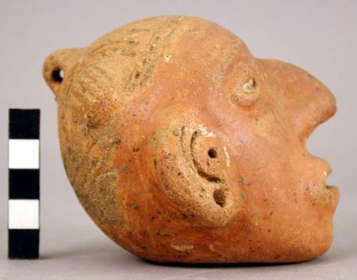 Red human head effigy rattle with elaborate headdress