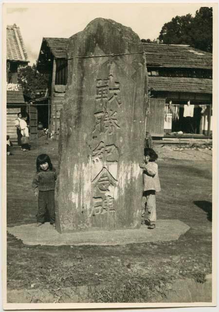 Children and stone monument with Shimenawa or sacred rope