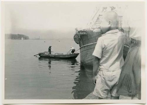 Boy on dock, with boats in background