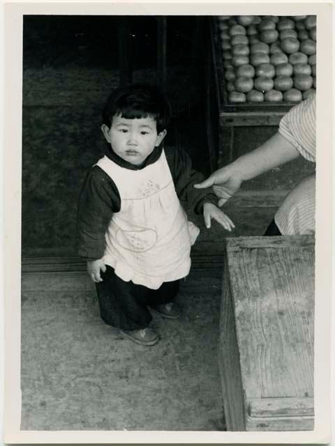 Child standing next to market stand