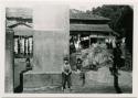 Children next to stone monument, with house in background