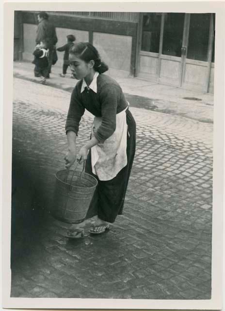 Girl sprinkling street in front of shop