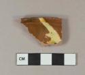 Yellow, light green, and brown slip decorated redware vessel rim fragment