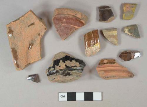 Lead glazed redware vessel base, rim, and handle fragments, 4 reddish brown lead glaze, 5 dark brown lustrous glazed, 2 yellow and brown slip decorated