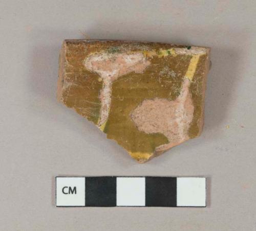 Yellow, green, and brown slip decorated redware vessel rim fragment, unglazed exterior